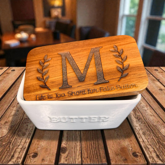 Wooden lid butter dish with personalized monogram and leaf designs on a wooden table.